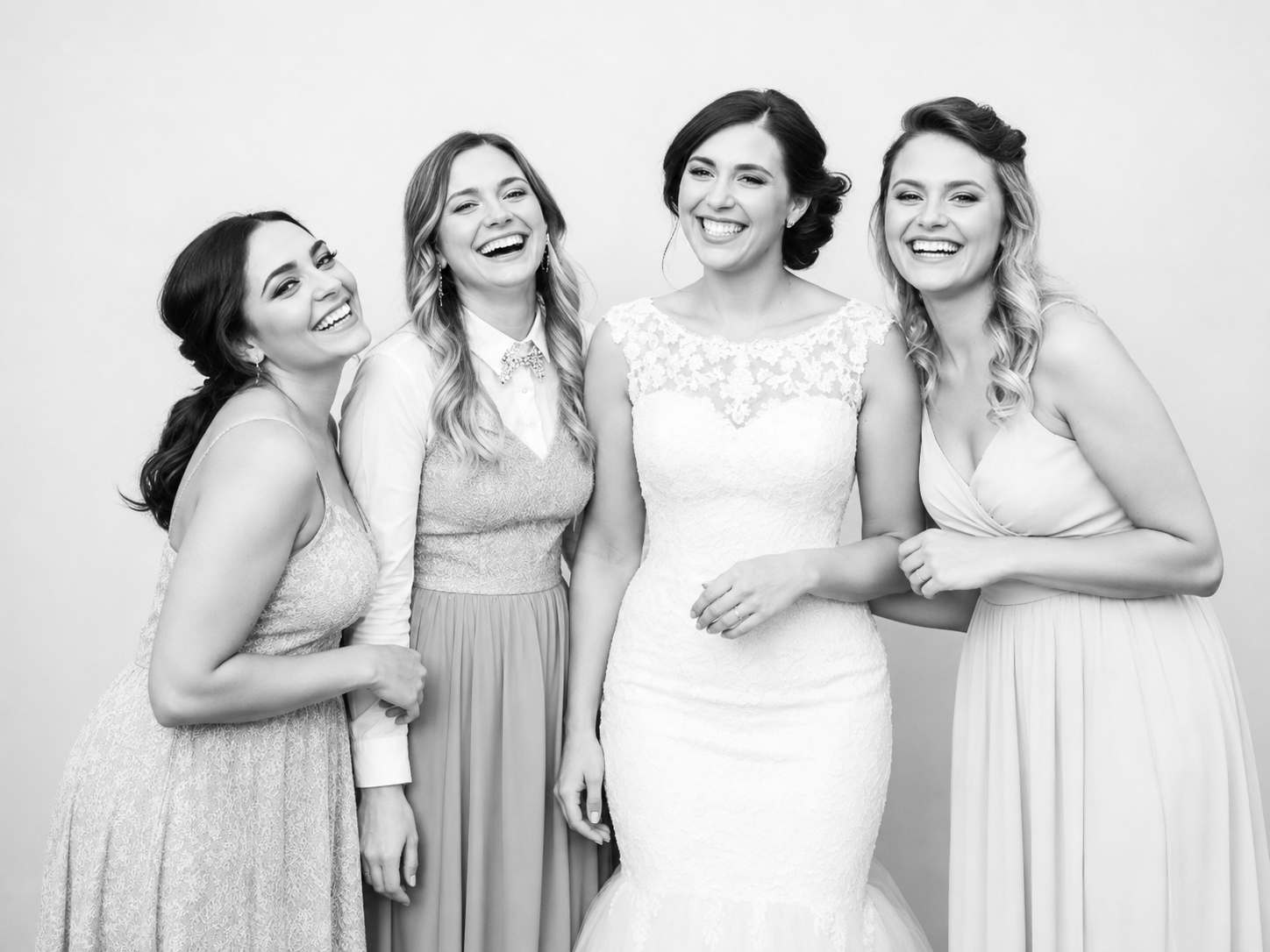 Black and white portrait of a bride and her bridesmaids laughing in the glam booth